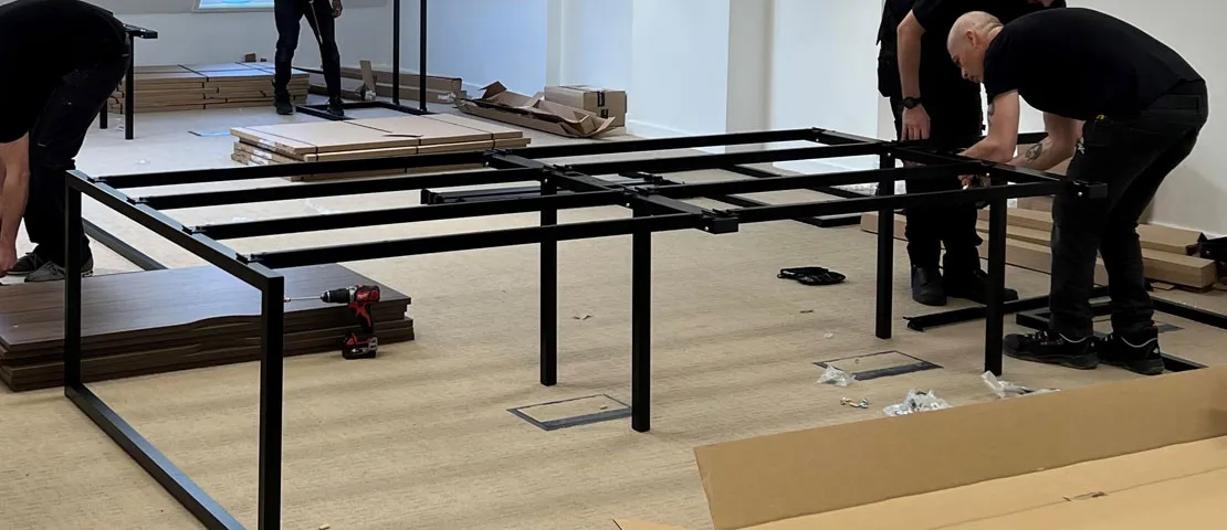 Installify fitters assembling bench desk frames in a new London office